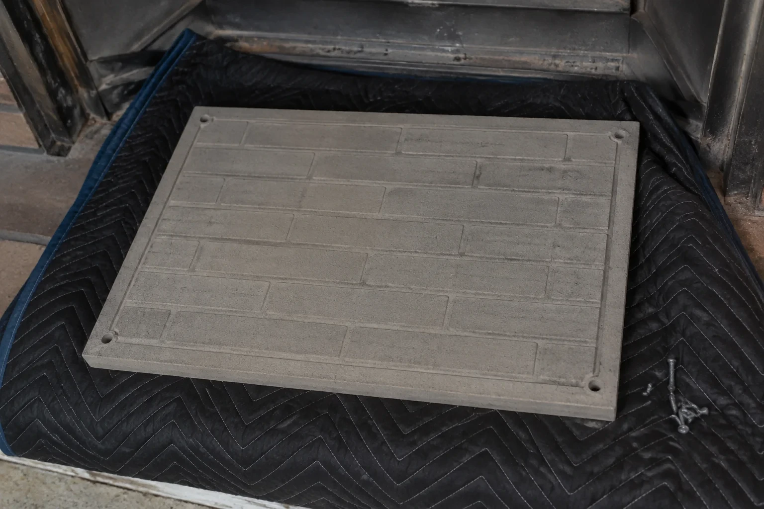 Detached refractory panel on a mat near a fireplace.